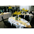 Oval table with white tablecloth, yellow flowers and table runners