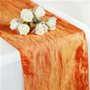 Orange crinkle tafetta table runeer on white tablecloth with flowers